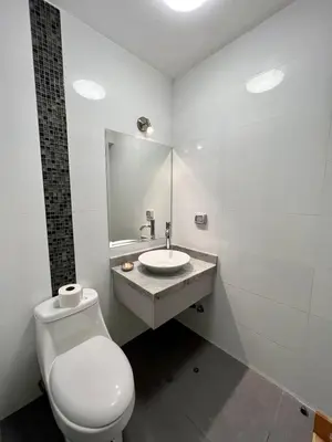 a white bathroom with a toilet and a sink at Malecón Miraflores Luxury Penthouse in Lima