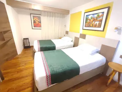 a hotel room with two beds and a table at Patrick's Day Home Cusco in Cusco