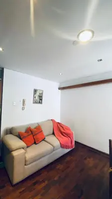 a living room with a couch with two orange pillows at Lindo departamento en Miraflores Parque Kennedy in Lima