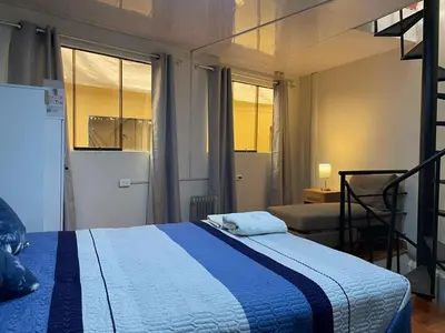a bedroom with a blue and white bed and windows at Minidepartamento de 3 pisos, completo y comodo in Cusco