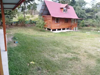 a house with a pink roof on top of a yard at Yoly cabaña in Oxapampa