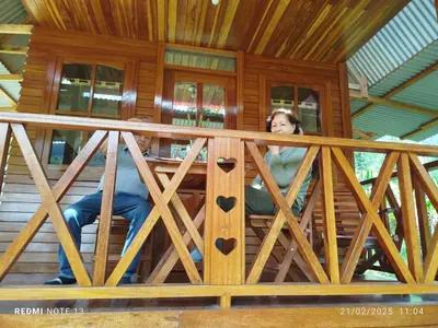 a woman sitting on the porch of a wooden house at Yoly cabaña in Oxapampa