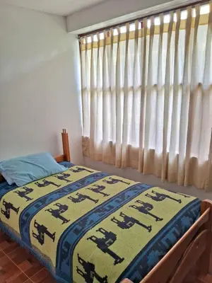 a bedroom with a bed and a window with curtains at Guest House Aylluq Wasin in Urubamba