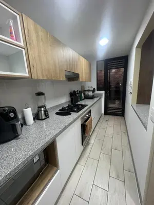 a kitchen with white counter tops and wooden cabinets at AMPLIO DEPARTAMENTO EN JESÚS MARÍa in Lima