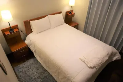 a bedroom with a white bed with two night stands at Casa Canal - 3 cuadras de la Plaza de Armas in Cusco