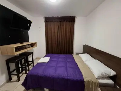 a bedroom with a bed and a desk and a television at Wayki House in Ica