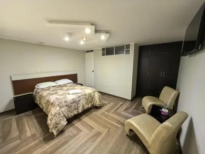 a bedroom with a bed and two chairs in it at Hotel Douce Nuit in Huancayo