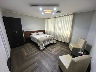 a bedroom with a bed and a chair at Hotel Douce Nuit in Huancayo