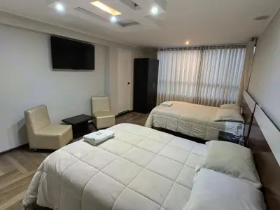 a hotel room with two beds and a television at Hotel Douce Nuit in Huancayo