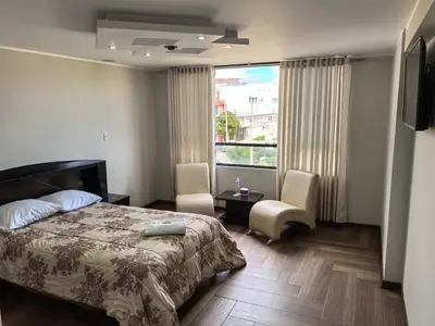 a bedroom with a bed and a large window at Hotel Douce Nuit in Huancayo