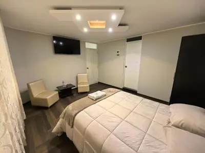 a bedroom with a bed and a table and chairs at Hotel Douce Nuit in Huancayo