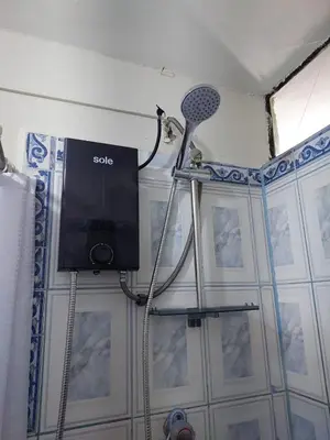 a bathroom with a shower with a tv on a wall at JTM Apartament in Cusco