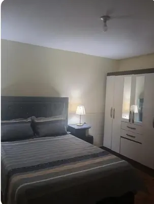 a bedroom with a bed and a lamp on a night stand at Departamento Acogedor en Surco in Lima