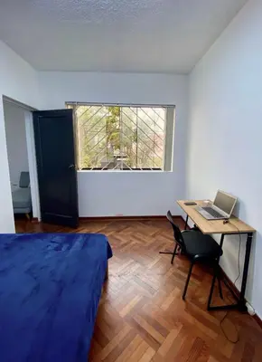 a bedroom with a bed and a desk with a laptop at Gutierrez Hostel in Lima