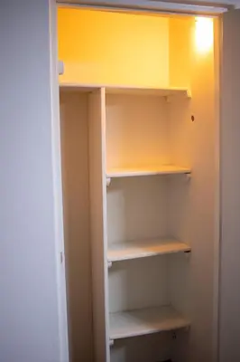 a small closet with yellow walls and white shelves at Gutierrez Hostel in Lima