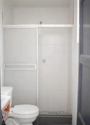 a white bathroom with a shower and a toilet at Gutierrez Hostel in Lima