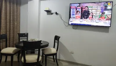 a room with a table and chairs and a tv on the wall at Apartment 10 minutes from the airport in Lima