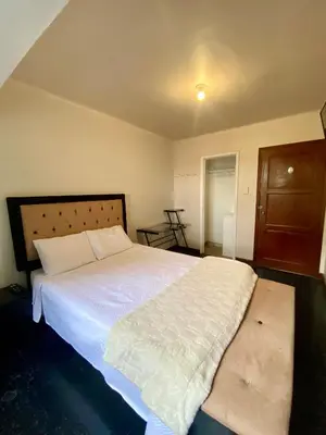 a bedroom with a large white bed and a wooden door at Habitaciones Independientes Av Larco in Lima