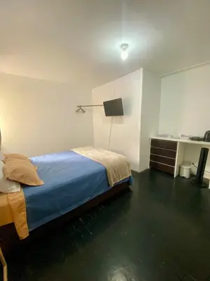 a bedroom with a bed and a desk with a lamp at Céntrica y amplia habitación queen Av Larco in Lima
