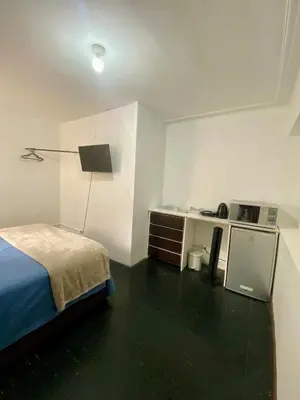 a bedroom with a bed and a desk and a lamp at Céntrica y amplia habitación queen Av Larco in Lima