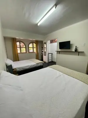 a hotel room with two beds and a television at Amplia habitación dos camas dobles Miraflores in Lima