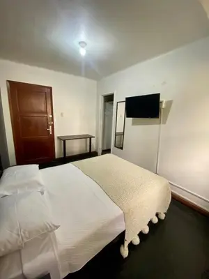 a bedroom with a white bed and a flat screen tv at Habitación céntrica con vistas Larco in Lima
