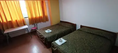 a hotel room with two beds and a window at Hostal Cesar Alberto in Lima
