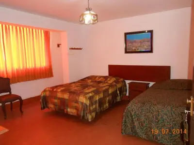 a hotel room with two beds and a window at Hostal Cesar Alberto in Lima