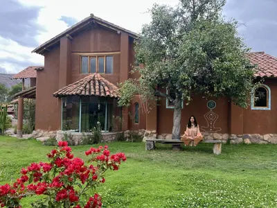 a woman sitting on a bench in front of a house at KinsaPacha in Urubamba