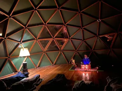 a person sitting in a room with a ceiling in a hexagonal tent at KinsaPacha in Urubamba