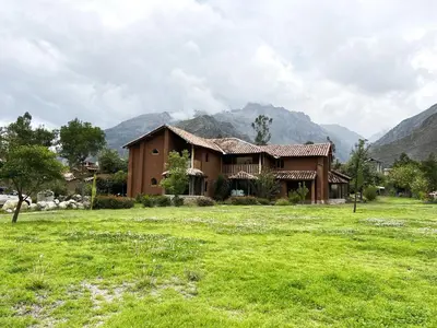 a house in a field with mountains in the background at KinsaPacha in Urubamba