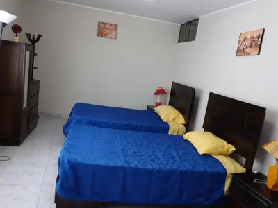 a bedroom with two beds with blue sheets and yellow pillows at Modern Apartmen Furnished in Lima Near the Airport in Lima