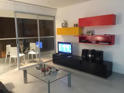 a living room with a tv and a glass table at Paracas Beach Vacation Rentals in Paracas