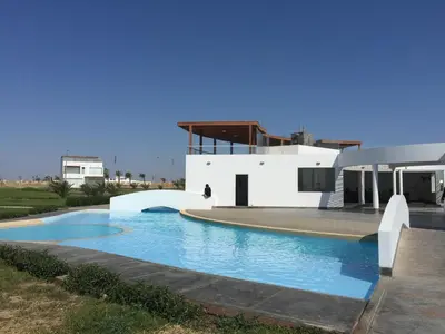 a swimming pool in front of a white house at Paracas Beach Vacation Rentals in Paracas