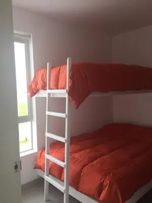 a white bunk bed with a ladder next to a window at Paracas Beach Vacation Rentals in Paracas