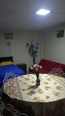 a table with a table cloth with a vase of flowers on it at Studio with kitchen and Bathroom Near The Airport in Lima