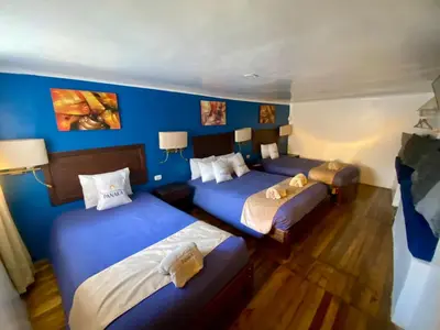 three beds in a room with blue walls and wooden floors at Hotel Panaka II in Cusco
