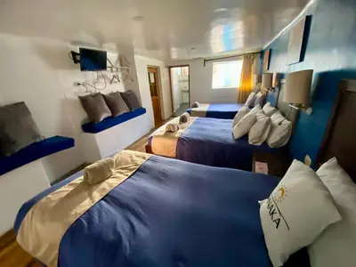 two beds in a room with blue and white at Hotel Panaka II in Cusco