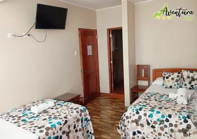 a bedroom with two beds and a tv on the wall at Destino Aventura Peru in La Merced