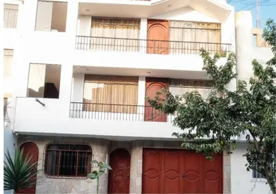 a white house with red doors and a tree at New Apartment furnished in Lima - Near the Airport in Lima