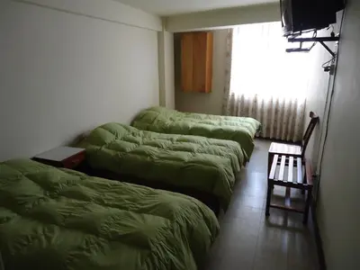 a room with four beds and a chair and a window at Hotel Estación Central in Lima