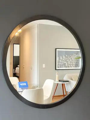 a mirror reflecting a living room with a table and white chairs at Barranco Sailor Apartment by Geko in Lima