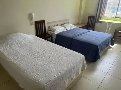 two beds in a hotel room with blue sheets at Hostal Skyblue in Asia