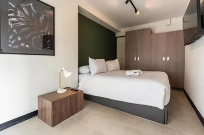 a bedroom with a bed and a table with a lamp at Rivera Navarrete by Geko in Lima