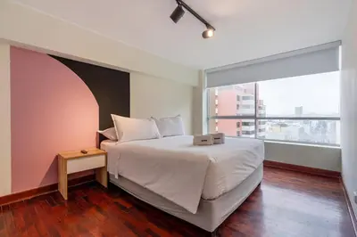 a bedroom with a large bed and a large window at Caoba 3BR by Geko in Lima