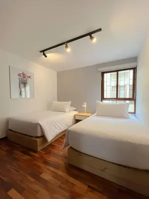 two beds in a white room with wooden floors at Wood House 3BR by Geko in Lima