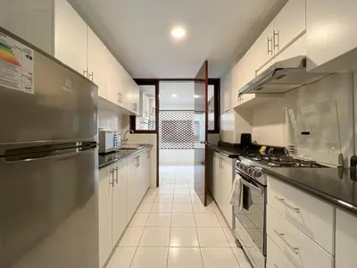 a large kitchen with white cabinets and stainless steel appliances at Wood House 3BR by Geko in Lima