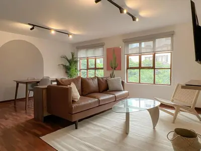 a living room with a brown couch and a table at Wood House 3BR by Geko in Lima