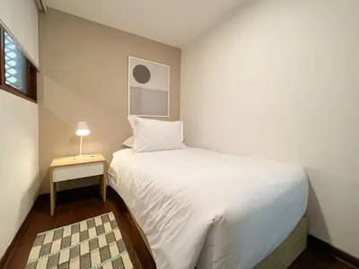 a small bedroom with a white bed and a table at Wood House 3BR by Geko in Lima