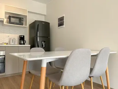 a kitchen with a table and chairs and a refrigerator at Syberia 2BR by Geko in Lima